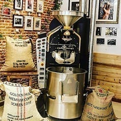Símbolo de Boconó Specialty Coffee junto al tostador de café