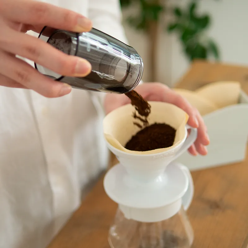 El recipiente del Hario Mini-Slim+ vierte café recién molido sobre el filtro de un dripper V60