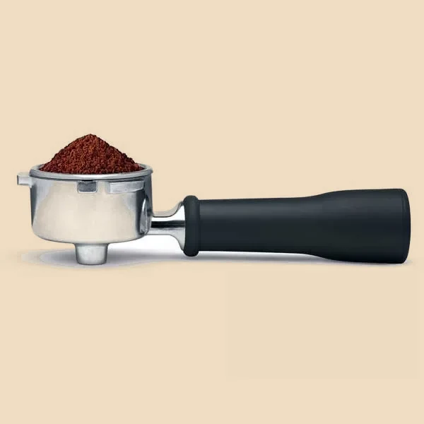 Portafiltros de la máquina con la dosis de café molido nivelada, listo para acoplar al grupo.