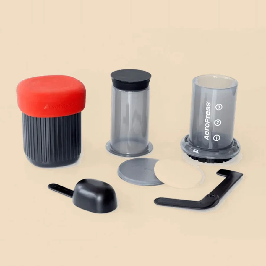 Todas las piezas de la cafetera de émbolo separadas: cámara, émbolo, vaso, tapa, cuchara y embudo.