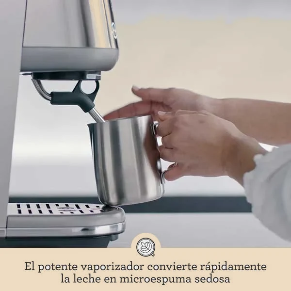 El vaporizador texturiza la leche dentro de una jarrita de acero sujeta con la mano.