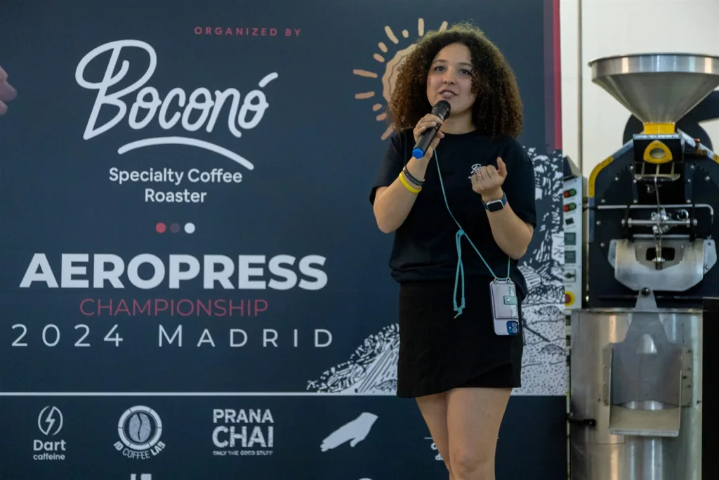 Presentadora con micrófono delante del photocall del campeonato, junto a la tostadora
