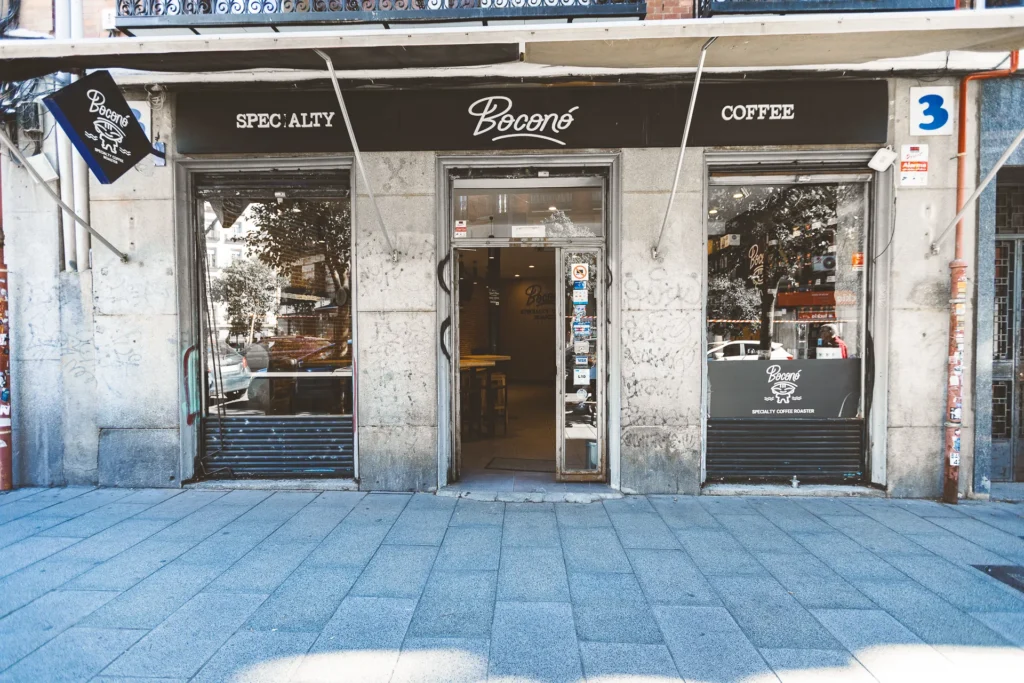 Fachada de Boconó Specialty Coffee en la calle Embajadores 3, en Madrid, con el rótulo Specialty Coffee, las puertas abiertas y el logotipo en el escaparate