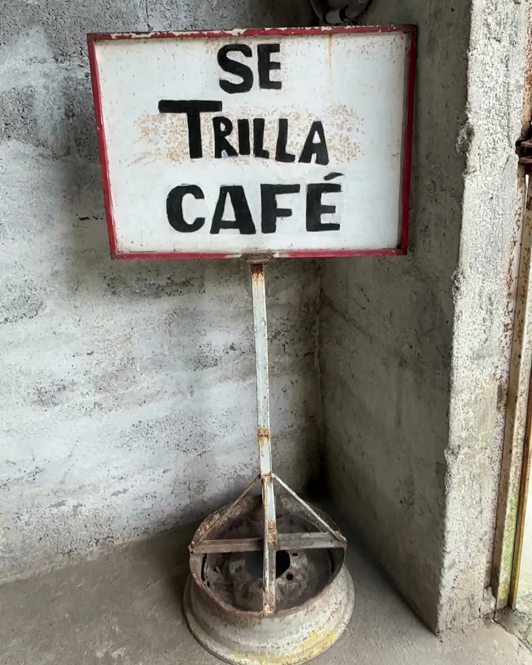 Cartel pintado a mano con el texto «Se trilla café», montado sobre una llanta vieja junto a una pared de bloques, en la finca Los Luises, en el estado Portuguesa, Venezuela