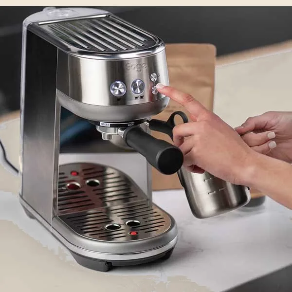 La máquina de espresso en una encimera mientras se coloca la jarrita de leche bajo el vaporizador.